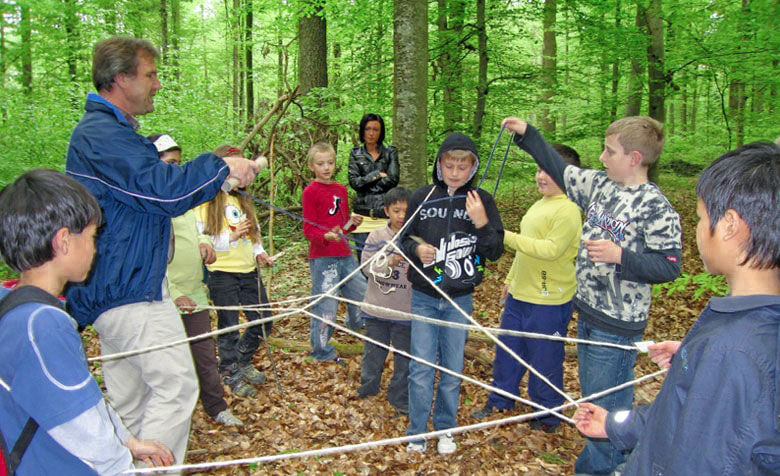 Schülerinnen und Schüler verbinden sich im Wald mittels eines Seils