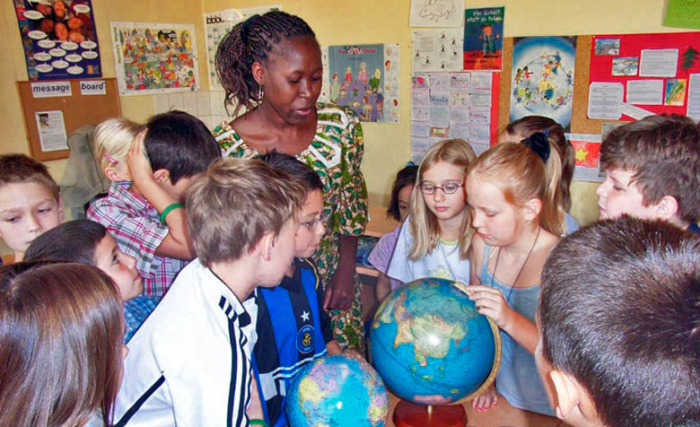 Schülerinnen und Schüler betrachten mit der Referentin einen Globus