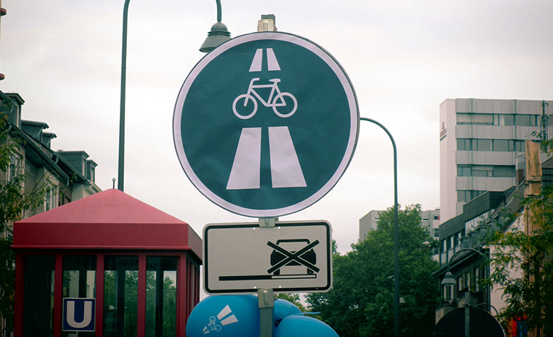 Ein Straßenschild in Köln zeigt zwei breite Fahrstreifen, die (nur) von einem Fahrrad befahren werden.