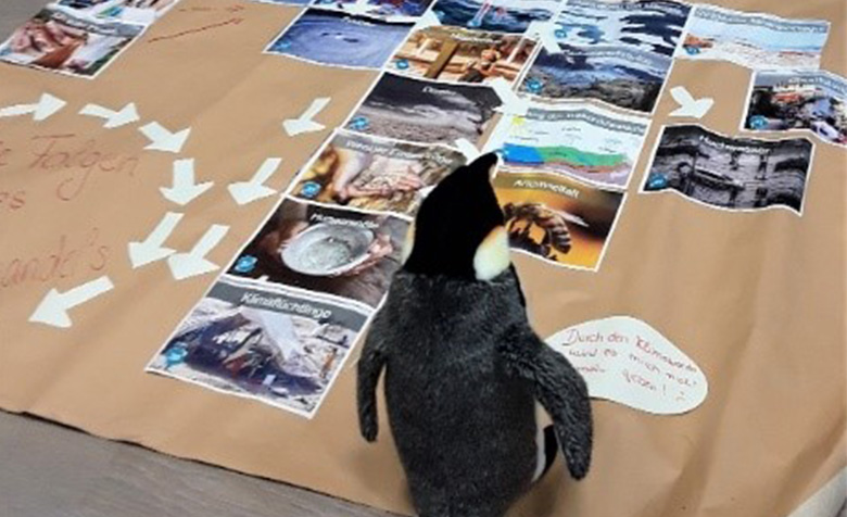Pinguin Rupert steht auf dem Klimapuzzle.