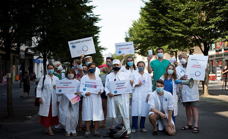 Eine Gruppe Menschen steht auf der Straße und hält Plakate zum Thema Klimaschutz und Gesundheit hoch.