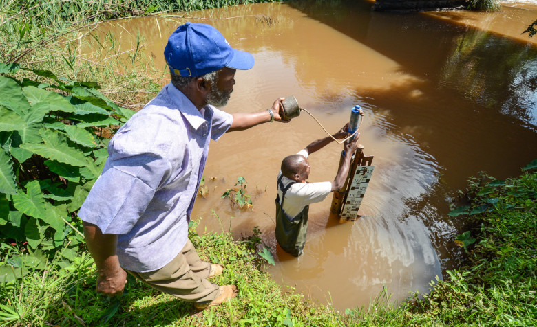 Zwei Männer entnehmen Wasserproben aus einem Fluss