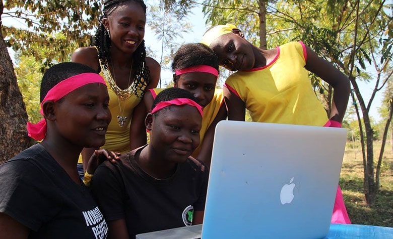 Fünf Schülerinnen schauen gemeinsam in einen Laptop