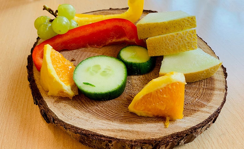 Eine Holzscheibe mit Obst, Gemüse und Käse