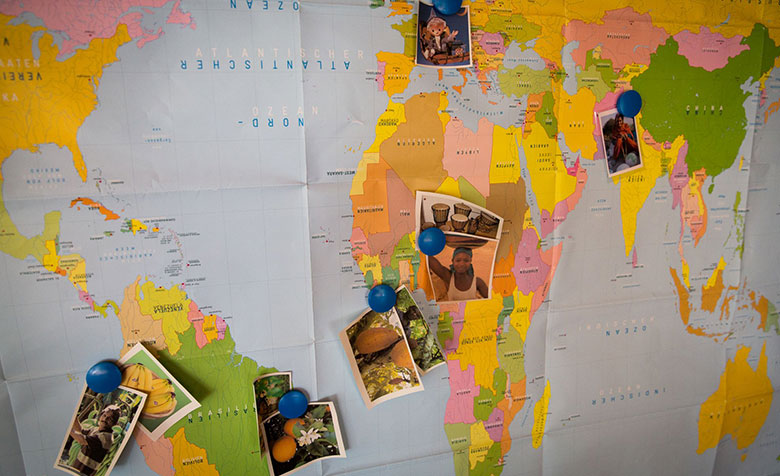 Eine Weltkarte, auf der Bilder mit Magneten befestigt sind.