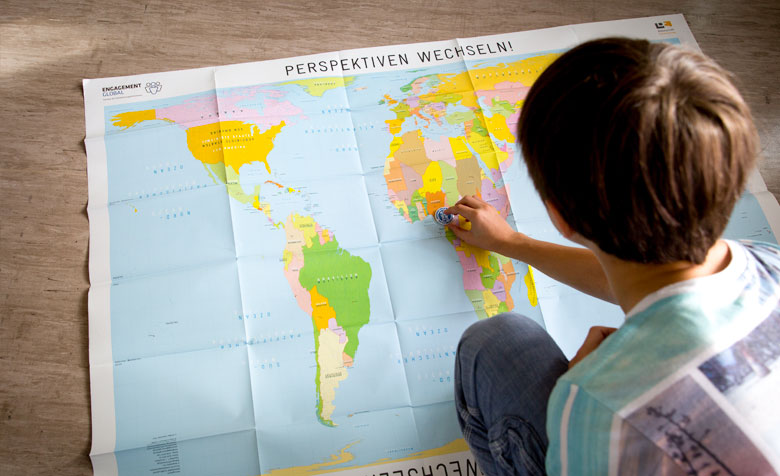 Ein Junge mit der Post-Ist auf eine Weltkarte klebt.