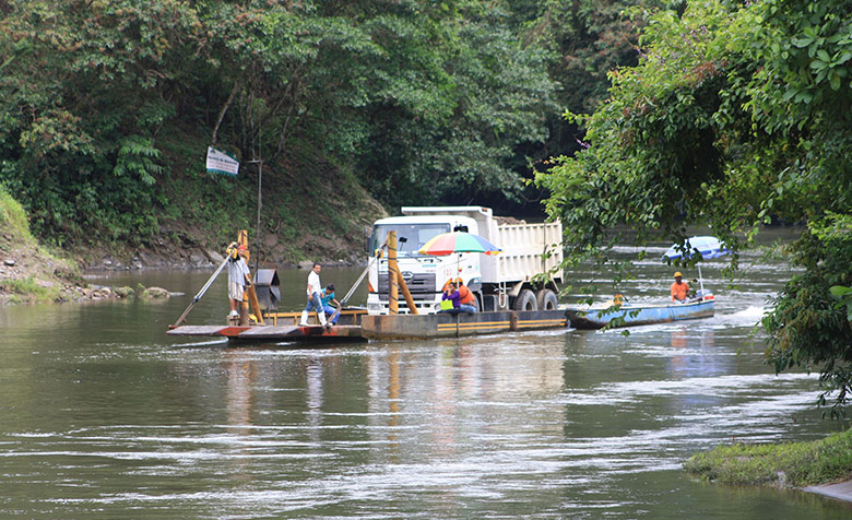 Ein Motorkayak transportiert einen LKW auf einem Fluss im ecuadorianischen Regenwald.