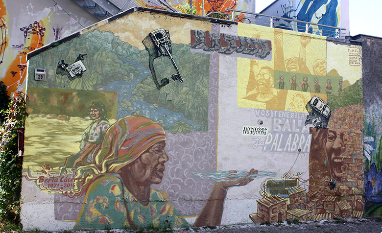 „Du hast die Kugel, wir das Wort“ heißt das Wandgemälde lateinamerikanischer Künstlerinnen und Künstler. Es gedenkt den Aktivistinnen  Berta Cáceres und Marielle Franco.